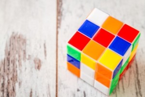Jigsaw puzzle rubik cube toy, multicolor plastic blocks on white wooden background