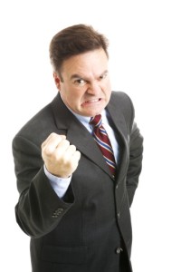 Businessman in his forties, angry and shaking his fist in a threatening way. Isolated on white.